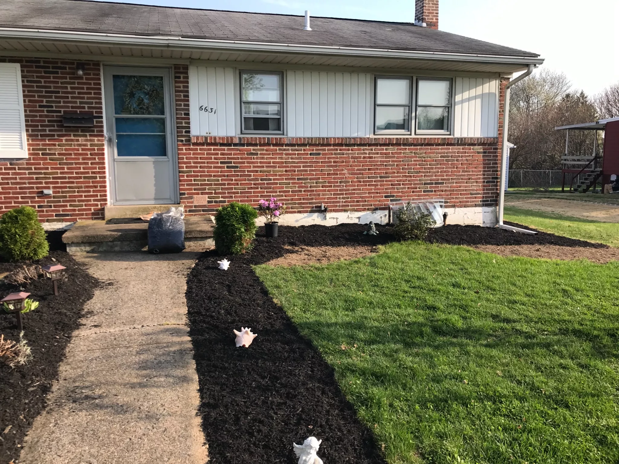 Brick ranch foundation beds freshly mulched black and edged along the walkway