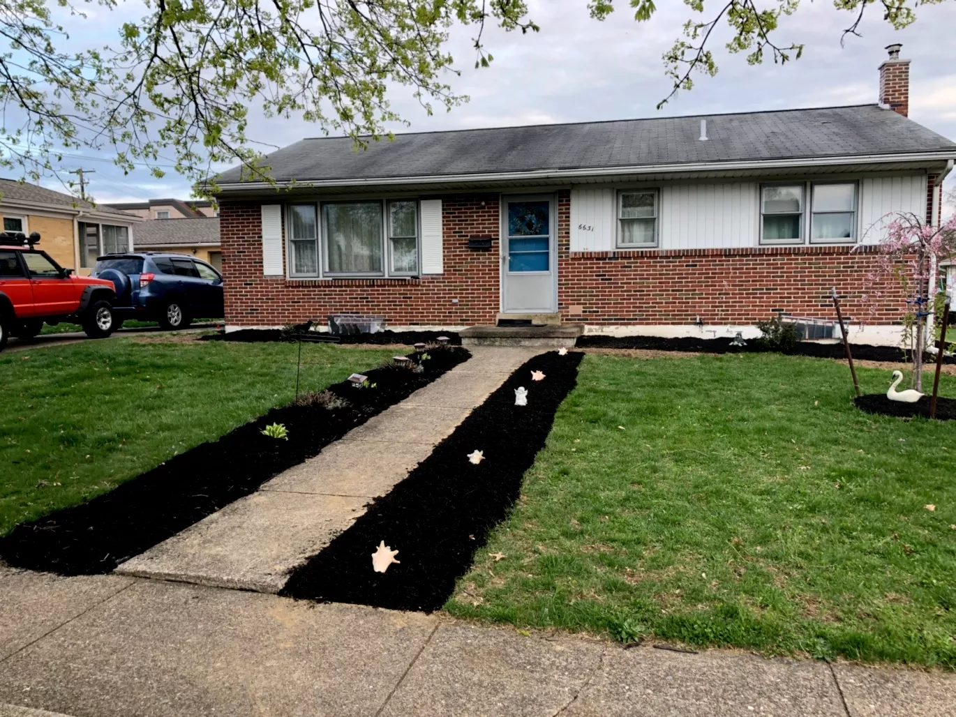Brick ranch home with fresh black-mulch beds framing the front walk and a mowed lawn